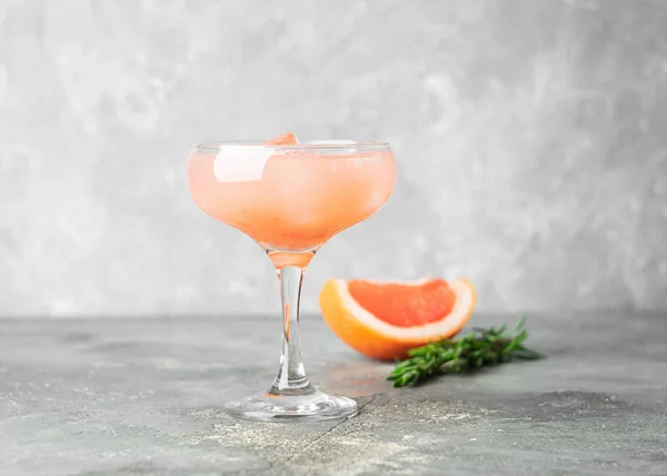 Cocktail estivo rinfrescante succo di rosmarino di pompelmo e ghiaccio in un calice di vetro su sfondo grigio cemento. Bere disintossicazione . — Foto Stock