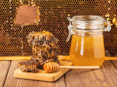 Masada ahşap arka plan üzerinde bir cam kavanoza taze kokulu tatlım. Arı bal farklı türleri. Doğal ürünler.