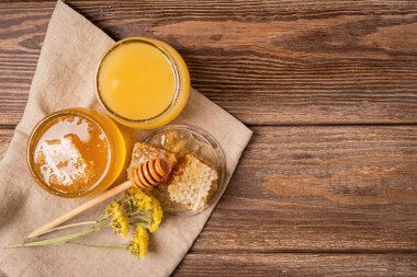 Altın taze bal kavanozlar ve peteğin ve bal kaşığı kahverengi ahşap arka plan ile. Doğal ürünler kavramı.