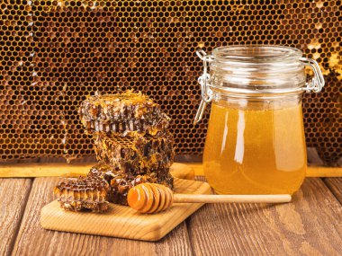 Masada ahşap arka plan üzerinde bir cam kavanoza taze kokulu tatlım. Arı bal farklı türleri. Doğal ürünler.