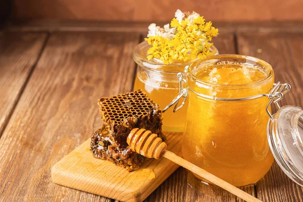 Čerstvý voňavý med ve skleněné nádobce na dřevěné pozadí na stole. Různé druhy medu, včel. Přírodní produkty. — Stock fotografie