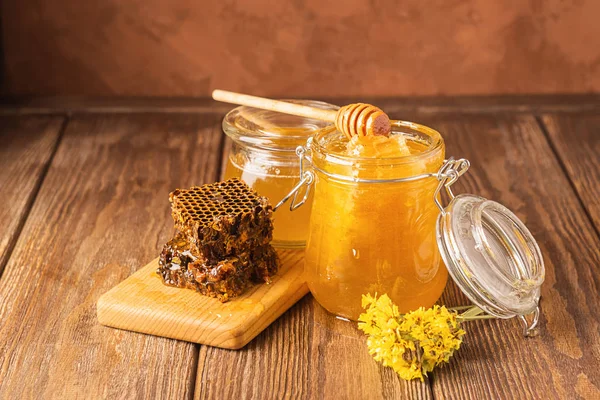 Miel fragante fresca en un frasco de vidrio sobre un fondo de madera sobre la mesa. Diferentes tipos de miel de abeja. Productos naturales . — Foto de Stock