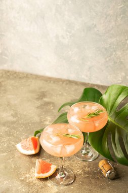 Greyfurt şampanya suyu cam kadehler gri beton arka plan canavar yaprakları ile bir serinletici yaz kokteyl.