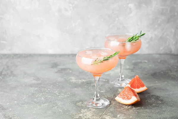 Un rinfrescante cocktail estivo di rosmarino di pompelmo e succo di ghiaccio in eleganti calici di vetro sfondo grigio cemento . — Foto Stock