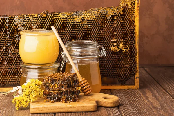 Miel fragante fresca en un frasco de vidrio sobre un fondo de madera sobre la mesa. Diferentes tipos de miel de abeja. Productos naturales . — Foto de Stock