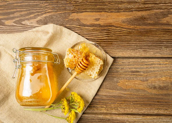 Färska doftande honung i en glasburk på en trä bakgrund på bordet. Olika typer av binas honung. Naturliga produkter. — Stockfoto