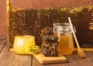 Ahşap masada çeşitli cam kavanoz ve petekler altın taze bal. Organik gıda konsepti. Rustik kahverengi arka plan