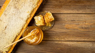 Ahşap bir masada bir cam kavanoz ve petekler altın taze bal. Doğal ürünler kavramı. rustik arka plan.