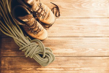 Bir çift kahverengi yıpranmış botları ve ahşap arka plan üzerinde bir spor ip. Seçici odak. Kavramı seyahat ve macera.