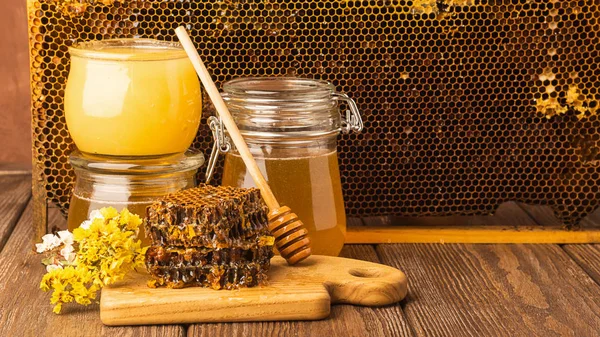 Verse geurige honing in een glazen pot op een houten achtergrond op tafel. Verschillende soorten bijen honing. Natuurlijke producten. — Stockfoto