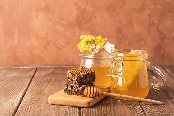 Miel fragante fresca en un frasco de vidrio sobre un fondo de madera sobre la mesa. Diferentes tipos de miel de abeja. Productos naturales . — Foto de Stock