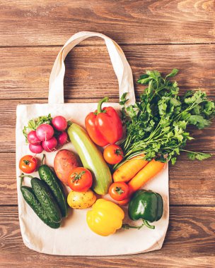 Doğal pamuk taze sebze ahşap arka plan yapılmış kolları ile Çanta. Sağlıklı ve doğru beslenme. Vejetaryenlik.