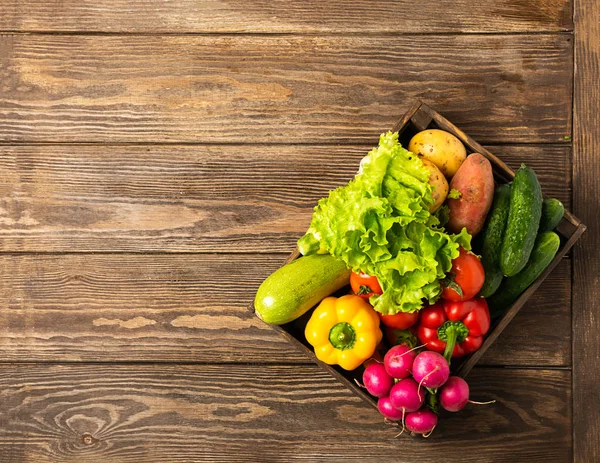 Fresh harvest ripe vegetables zucchini cucumber greens pepper in box on a wooden background. Healthy food vegetarianism.