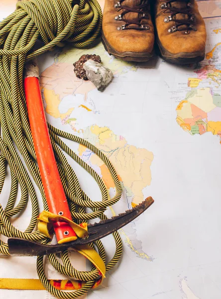 Sports equipment for high-altitude climbing boots ice ax rope on the background of a geographical map. Concept of travel