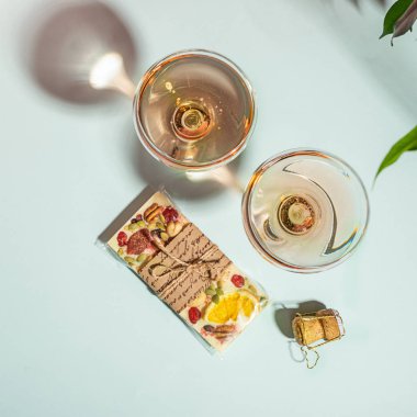 İçecek şampanya veya şarap iki zarif bardak ve beyaz çikolata nazik mavi arka plan bir bar. Kavram minimalizmi.