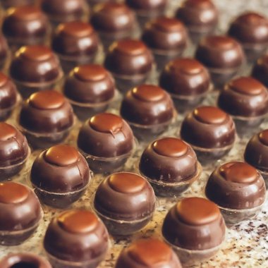 Koyu çikolata şekerler özel şekillerde sıralar halinde düzenlenmiştir. El yapımı çikolatalar pişiriyorum. Seçici odaklama.