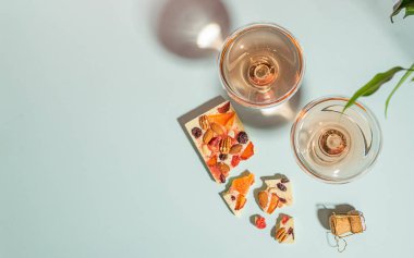 İçecek şampanya veya şarap iki zarif bardak ve beyaz çikolata nazik mavi arka plan bir bar. Kavram minimalizmi.