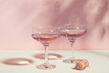 Pembe arka plan parlak ışık üzerinde zarif bardak şampanya veya şarap. Kopya alanı. Seçici odaklama.