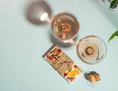 İçecek şampanya veya şarap iki zarif bardak ve beyaz çikolata nazik mavi arka plan bir bar. Kavram minimalizmi.
