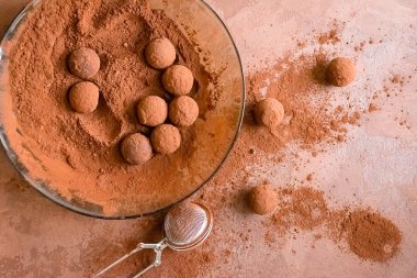 Tabakta el yapımı çikolatalı yer mantarı. Koyu kahverengi arka plan üzerinde kakao tozu koyu çikolata şekerler. Düz düzen.