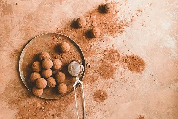 Tabakta el yapımı çikolatalı yer mantarı. Koyu kahverengi arka plan üzerinde kakao tozu koyu çikolata şekerler. Düz düzen.