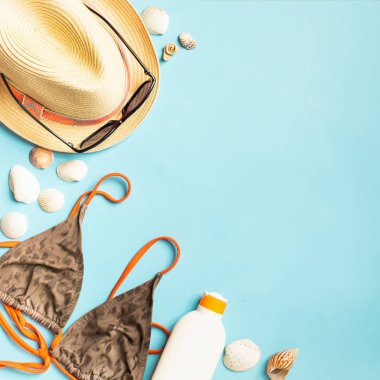 Yaz plaj aksesuarları güneş kremi şapka mayo parlak mavi arka plan . Plajda dinlenme kavramı.