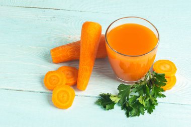 Ahşap mavi bir arka plan üzerinde taze havuç suyu bir bardak. Seçici odak. Kopyalama alanı.