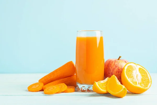 Vers sap van wortelen en sinaasappel appels in een glas op een houten blauwe achtergrond. Selectieve focus. Ruimte kopiëren. — Stockfoto