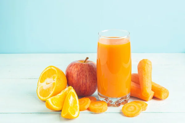 Świeży sok z marchwi i pomarańczowych jabłek w szklance na drewnianym niebieskim tle. Selektywne skupienie. Kopiuj przestrzeń. — Zdjęcie stockowe