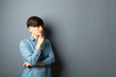 Gri boş bir arka plan üzerinde kısa bir saç kesimi ile genç bir kadının portresi. İnsan duyguları yüz ifadesi hüzün