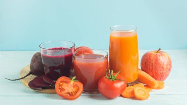 Ahşap mavi arka plan üzerinde gözlük sebze pancar elma havuç domates çeşitli taze meyve suyu smoothies.