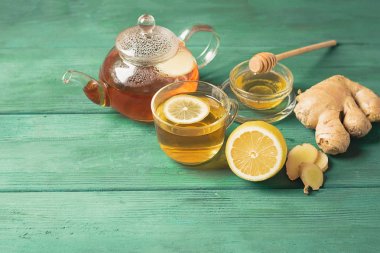 Bir cam fincan bal ve ahşap rustik arka plan üzerinde bir çaydanlık ile Çay limon zencefil. Detoks sağlığı için sağlıklı içecek.
