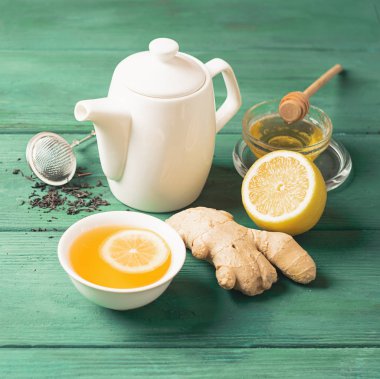 Beyaz porselen fincan çay limon zencefil ve ahşap bir arka plan üzerinde bir çaydanlık. Detoks sağlığı için sağlıklı içecek.