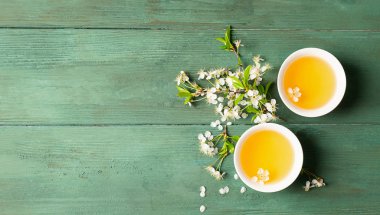 Ahşap arka plan üzerinde beyaz porselen bardak yaprakları ile kokulu çiçek çayı. Düz düzen üst görünümü. Kopyalama alanı.