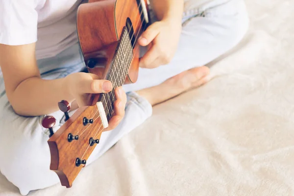 Hands girls play the guitar. A child learns to play the guitar. Selective focus. Close-up. The concept of music and art