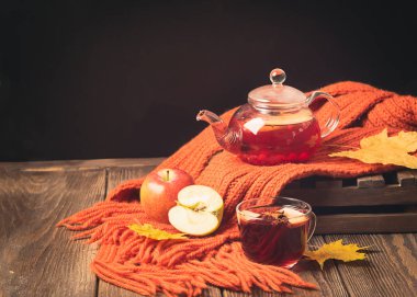 İçecek sonbahar elma kırmızı çilek bir cam çaydanlık ve ahşap bir arka plan üzerinde bir portakal eşarp. Sıcak meyve berry çay.