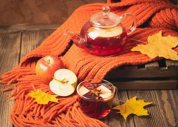 Пейте осенние яблочно-красные ягоды в стеклянном чайнике и оранжевый шарф на деревянном фоне. Горячие ягоды . — стоковое фото