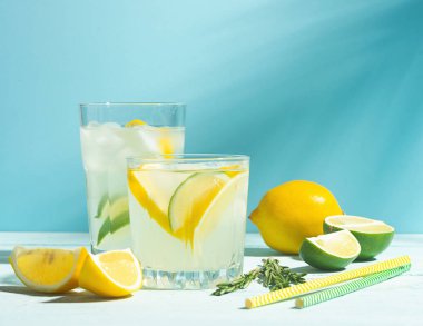 Şeffaf gözlük limonata bir içki mavi arka plan parlak güneş ışığı. Yaz kokteyli veya mojito.