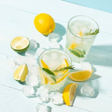 Şeffaf gözlük limon ve limonata bir içki mavi arka plan parlak güneş ışığı. Yaz kokteyli veya mojito.