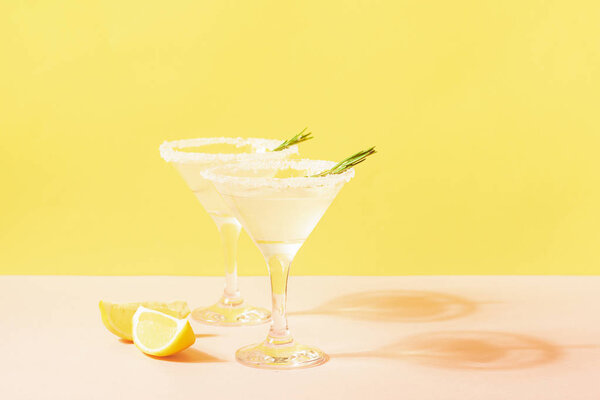 Лимонный лимонад в элегантных стаканах на ярком пастельном фоне. Яркое солнце. Летняя концепция
.