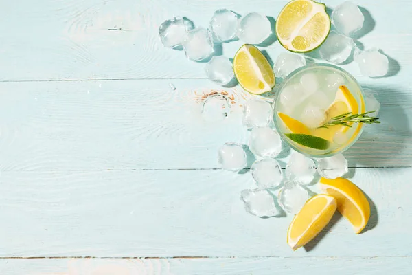 A drink of lemon and lime lemonade in transparent glasses blue background bright sunlight. Summer cocktail or mojito. — Stock Photo, Image