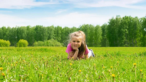 Retrato de una niña que yace en un prado verde en hierba fresca. Concepto de verano. Enfoque selectivo. Copiar espacio . — Foto de Stock