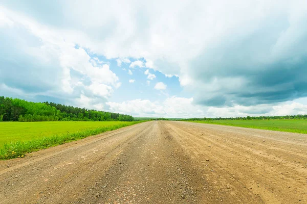 Paisagem estrada rural e céu azul. Estrada de cascalho recta que conduz ao horizonte . — Fotografia de Stock