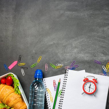 Sandviç şişe su öğretim malzemeleri bir tebeşir tahtası üzerinde defter kalem. Kavram okula geri döndü. Üst görünüm düz düzen.
