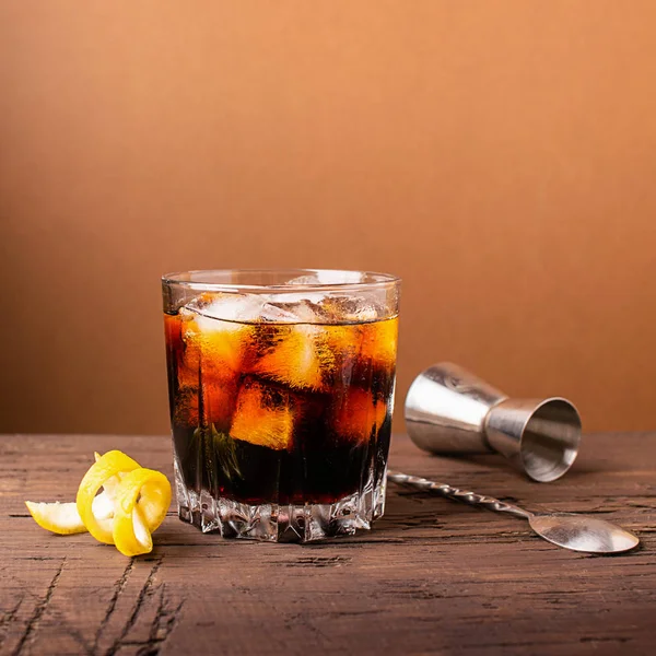 Bevanda alcolica forte di whisky di brandy in un bicchiere con cubetti di ghiaccio sfondo di legno scuro. Concentrazione selettiva. Copia spazio . — Foto Stock