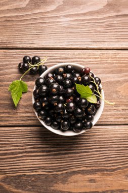 Koyu ahşap arka planda beyaz bir bardak taze siyah frenk üzümü. Dikey çerçeve