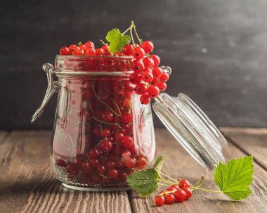 Ahşap bir masada bir cam kavanozda taze Olgun kırmızı frenk üzümü Berry. Seçici odak.