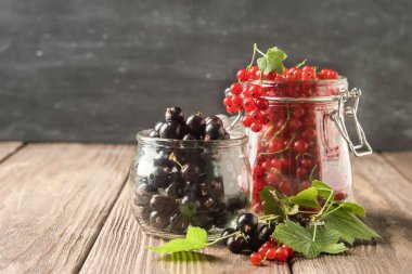 Karanlık bir arka planda çeşitli cam kavanozlarda taze Olgun kırmızı siyah frenk üzümü Berry. Yatay çerçeve. Seçici odak.