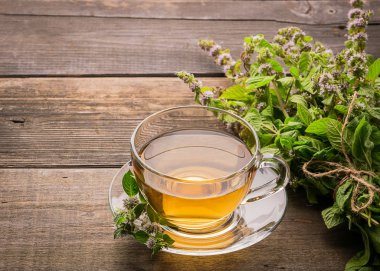 Ahşap rustik bir arka plan üzerinde melissa nane yaprakları ile taze çay Fincan. Şifalı bitkisel içecek. Yatay çerçeve.