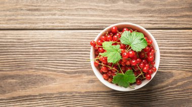 Koyu ahşap bir arka plan üzerinde beyaz bir fincan taze olgun kırmızı frenk üzümü berry. Yatay çerçeve. Kopyalama alanı.